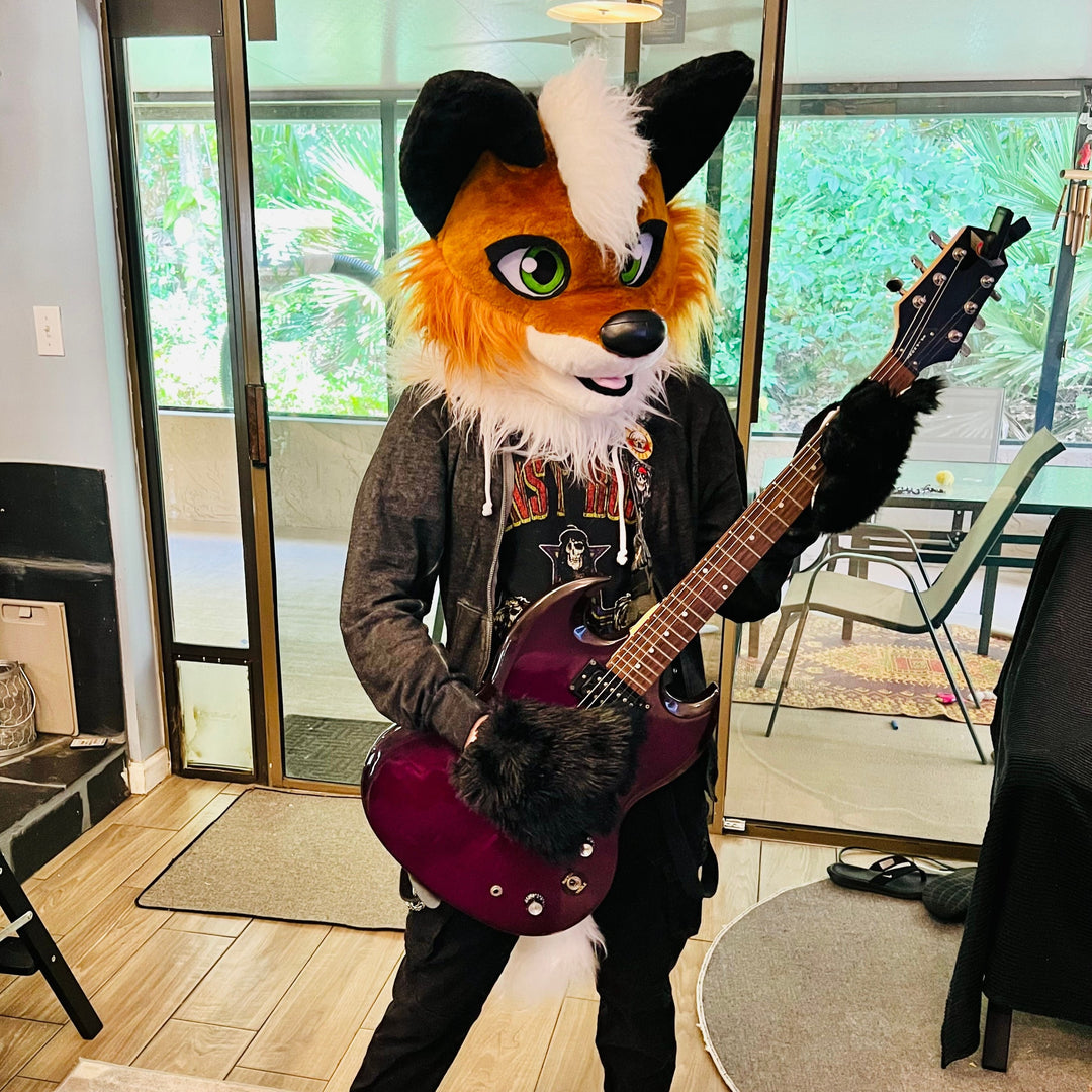 Teenager playing guitar in a fox fursuit head