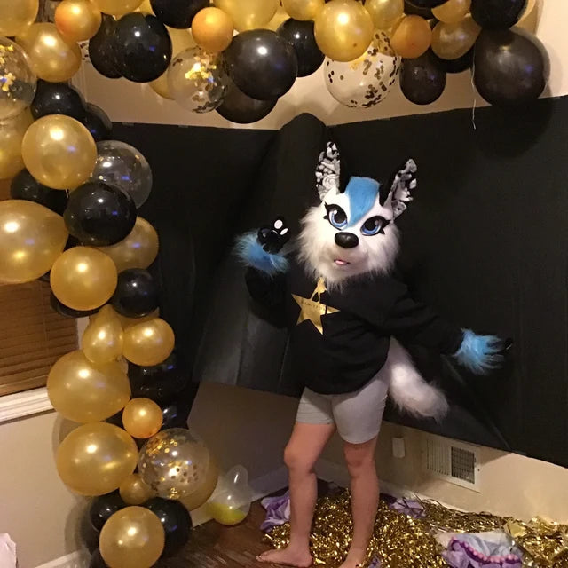 Girl in a white wolf fursuit head, hand paws and tail with air baloons