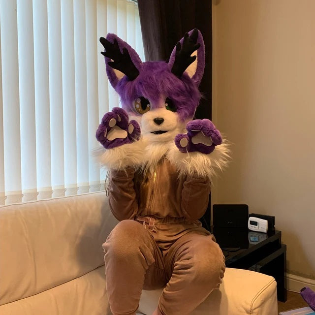 Kid in a lilac kemono fursuit head with horns sitting in the living room