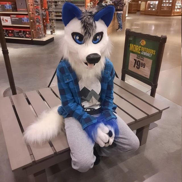 Boy in a white wolf fursuit sitting on a bench in a supermarket