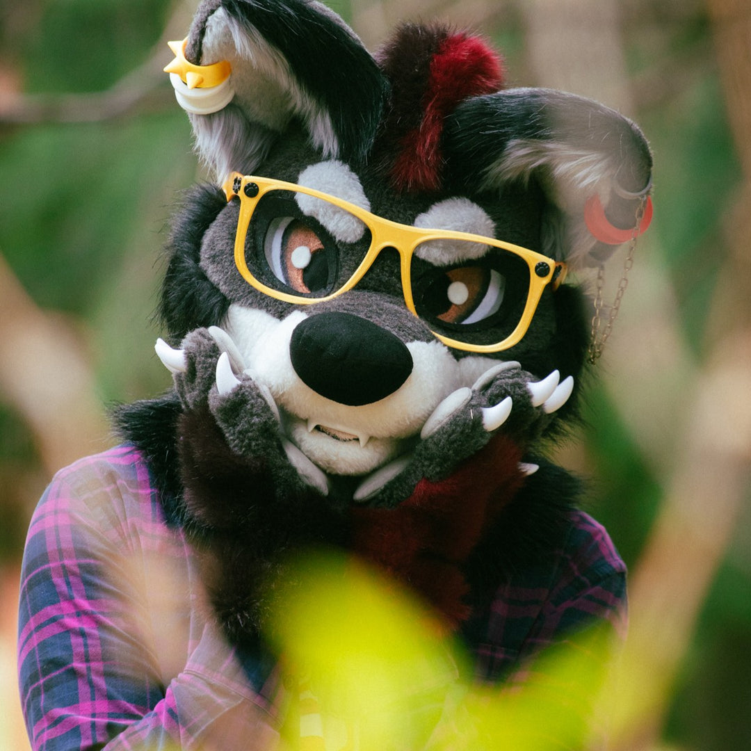 a portrait of a person wearing gray red wolf fursuit head with yellow glasses